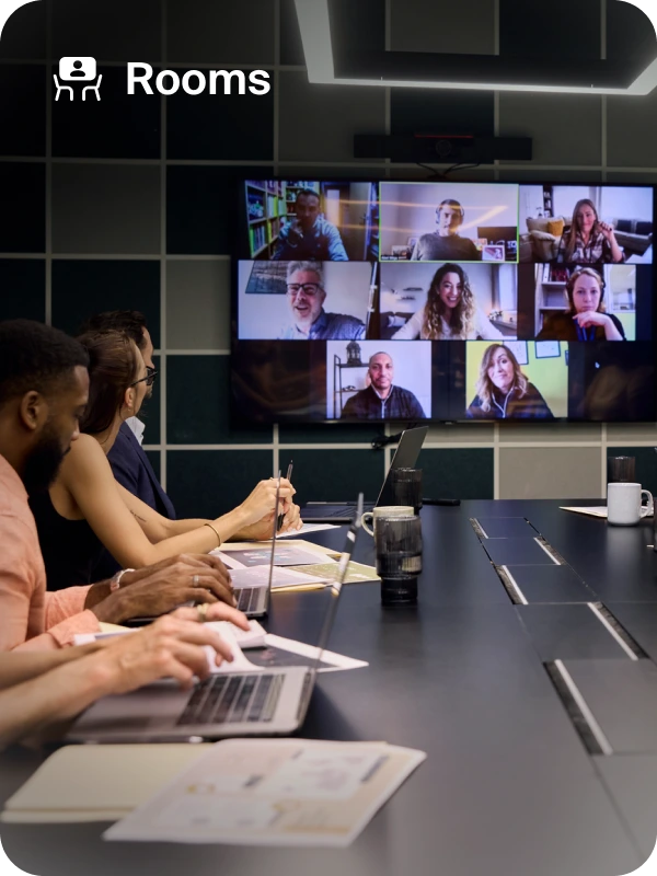 Des personnes réunies dans une salle de conférence Zoom discutent, tandis qu’un grand écran affiche du contenu visuel.